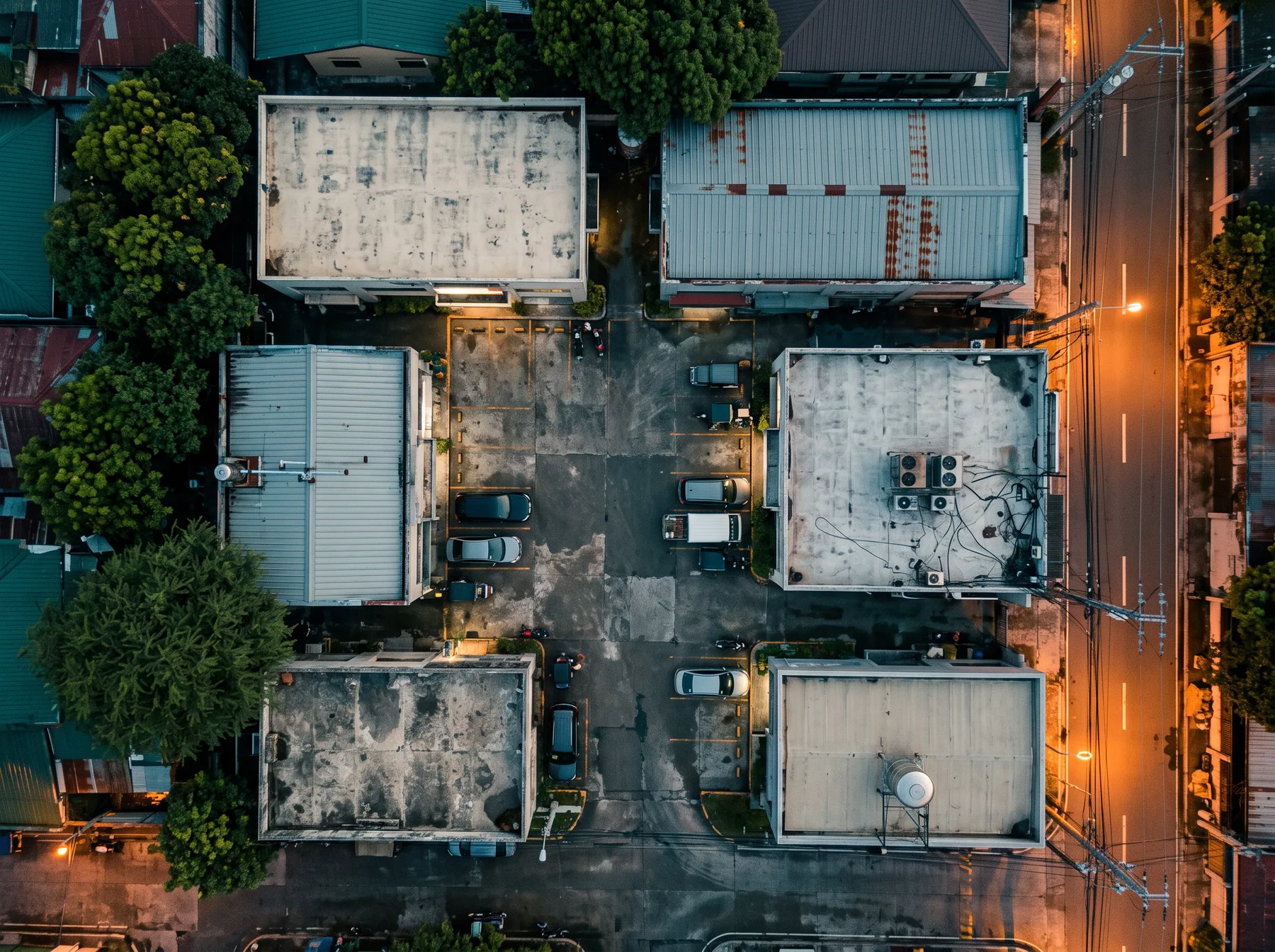Aerial view at dusk of a compound of six low-rise commercial buildings around a shared parking courtyard
